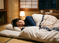 Woman sleeping on a futon mattress in a traditional Japanese room