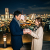 夜景の前で夫が妻にプレゼントを渡す