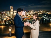 夜景の前で夫が妻にプレゼントを渡す