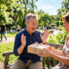 Woman giving a wrapped gift to an excited man on a park bench